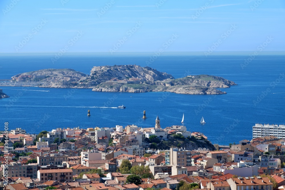 Aerial panoramic view of beautiful Marseille, France under blue sky; small island and city on the sea