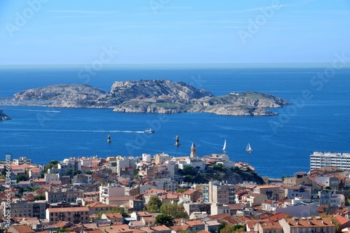 Aerial panoramic view of beautiful Marseille, France under blue sky; small island and city on the sea