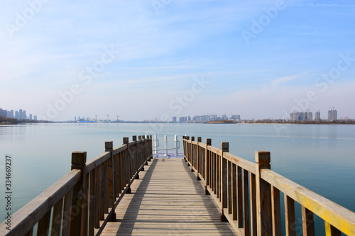 Secnery of lake and city on a sunny day  wooden bridge extending to the lake