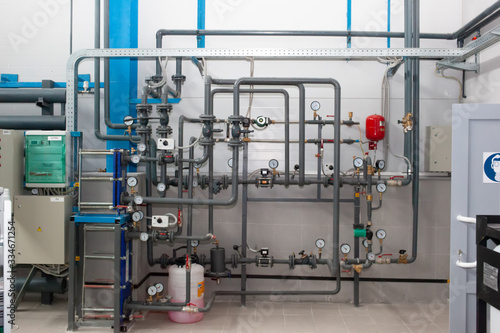 Heating system's cooper pipes with ball valves and manometer on a grey wall