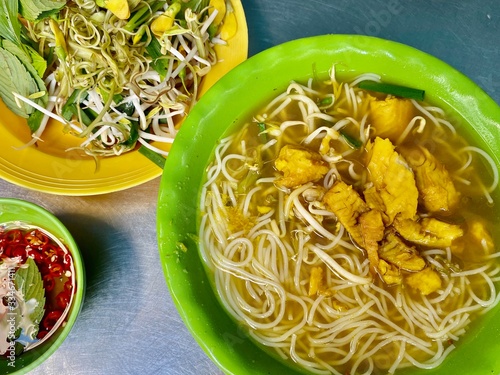 Vietnamese Chau Doc city bun ca loc snake head fish rice noodle soup bowl and different vegetable photo