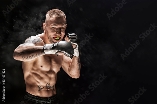 Fototapeta Mixed martial artist posing on a black background