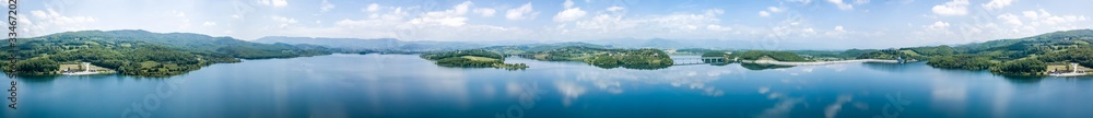 Panorama of green mountains and lakescape; the reflection of beautiful clouds and blue sky