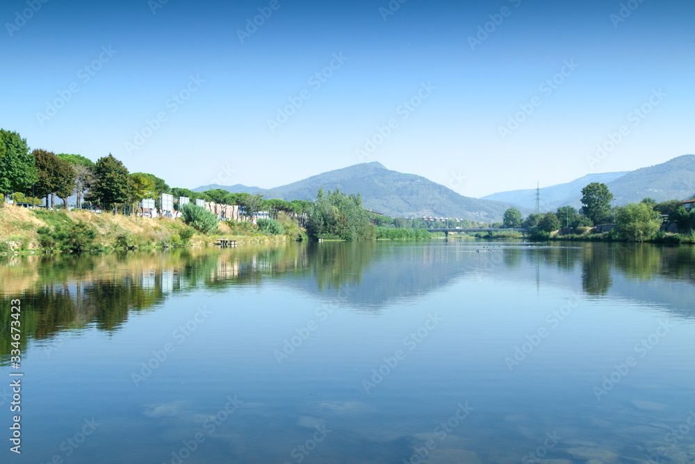 Beautiful natural lakescape under blue sky. Mountains and trees reflecting on the water