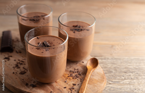 Homemade chocolate mousse made of dark chocolate,eggs, fresh cream and sugar on a wooden table. Top view.
