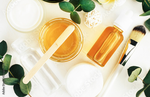 Cosmetic jars of golden honey for making natural skincare cosmetics, face and body beauty therapy, eucalyptus leaves, top view. Home spa treatment. 