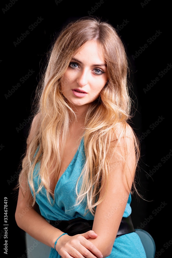 Foto Stock ritratto ragazza bionda sexy con occhi azzurri su sfondo nero,  posa di una donna bionda con occhi azzurri italiana in primo piano che posa  con atteggiamento sexy su sfondo nero