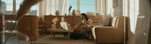 Fotografia Mother working from home, having a phone call, while her daughters distract her