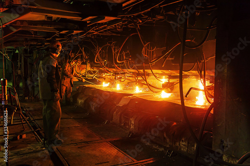 Workers at the metallurgical plant clean five steel feed channels in a continuous casting machine.