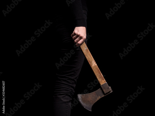 Girl holding in hand throwing axe on black background (ID: 334682607)