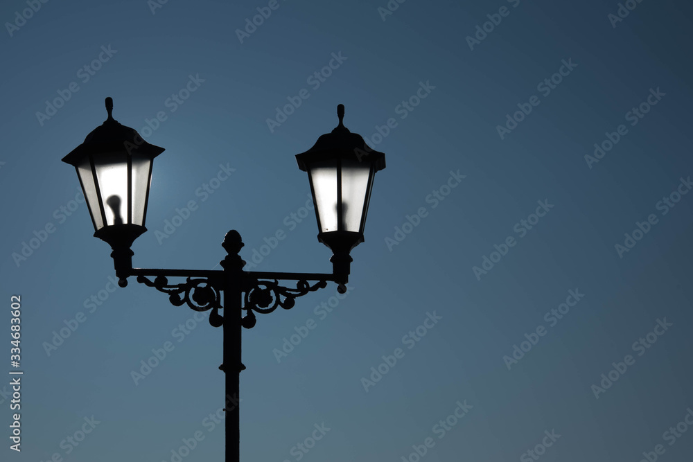 Urban landscape. Street lamp with a lamp in a classic style against a purple sky. Beautiful postcard.