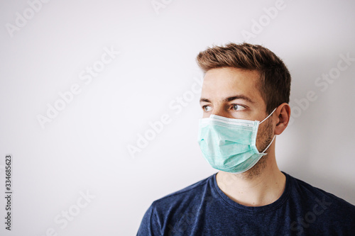 Portrait of young man with mask, looking away. Stay at home, home alone. Quarantine.