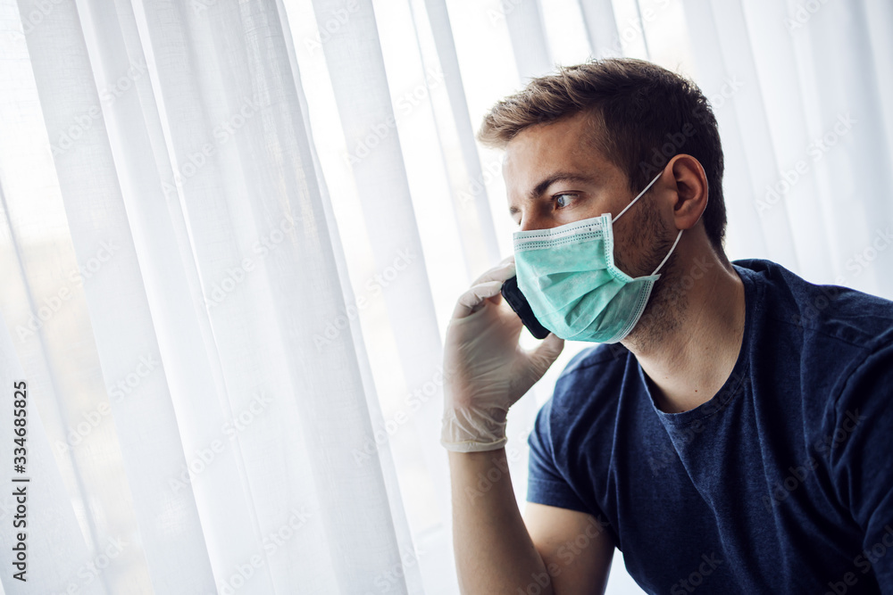 Young man with mask and gloves looking at mobile phone typing and looking worried. Reading bad news. Stay at home, world pandemic. Quarantine. Young man with mask and gloves looking at mobile phone typing and looking worried. Reading bad news. Stay at home, world pandemic. Quarantine.
