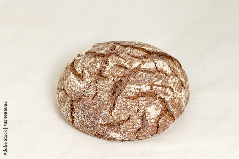 Gray round loaf of rye bread, an assortment of bread and bakery products. Closeup on a light background Gray round loaf of rye bread, an assortment of bread and bakery products. Closeup on a light background