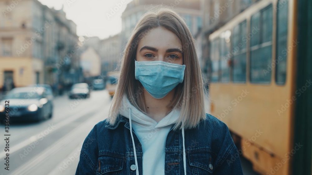 Portrait of a girl standing and putting on a protective mask on the street. Concept of health and safety life N1H1 covid19 coronavirus virus protection pandemic outdoor Portrait of a girl standing and putting on a protective mask on the street. Concept of health and safety life N1H1 covid19 coronavirus virus protection pandemic outdoor