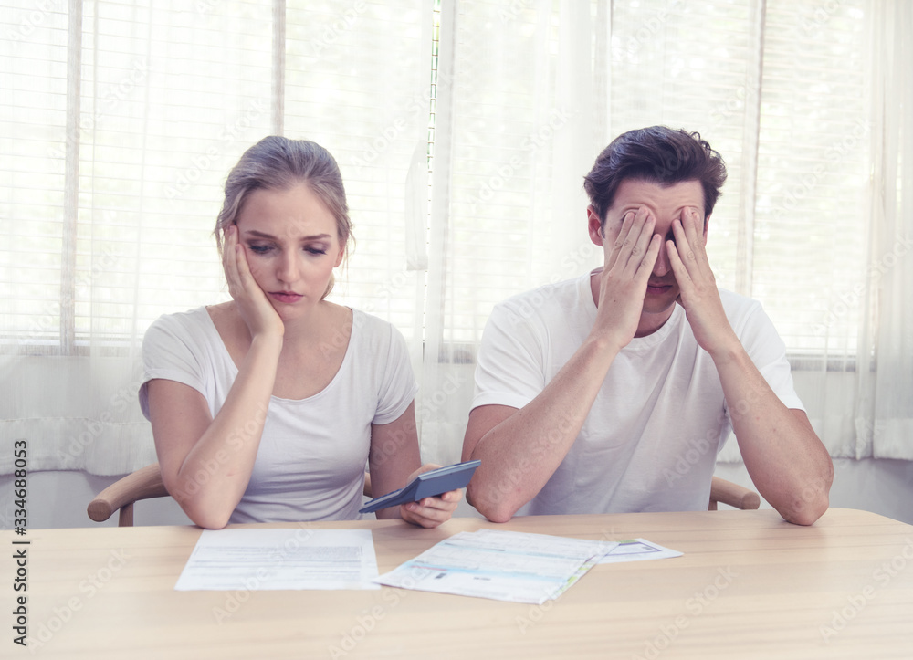 Young caucasian couple hand holding credit card and debt bill on table in home,men and women have overdue financial foreclosure problem sit in room with serious and unhappy payment. Young caucasian couple hand holding credit card and debt bill on table in home,men and women have overdue financial foreclosure problem sit in room with serious and unhappy payment.