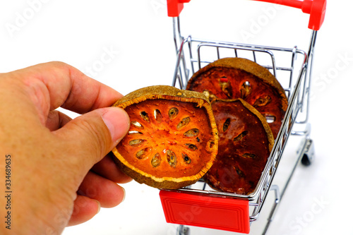 Hand putting dried bael fruit slice into shopping cart. photo