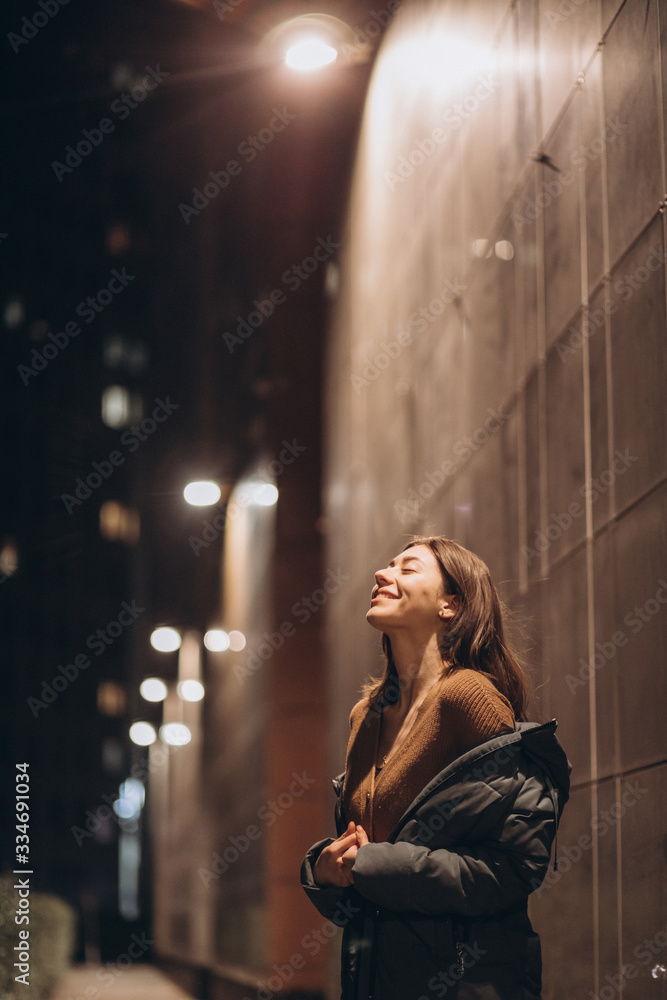 beautiful young brunette woman on a background of a night city in a down jacket beautiful young brunette woman on a background of a night city in a down jacket