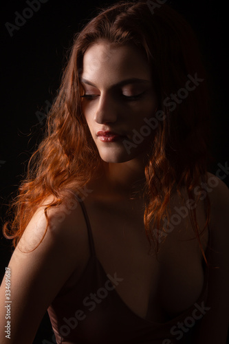 Portrait of a young curly girl in a dark studio