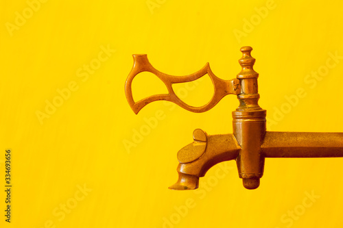 Vintage copper faucet on a bright yellow background. Concept with antique tap and copy space.