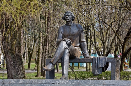 Monument to Maxim Gorky in Minsk. Maxim Gorky Park. The bench is mounted on a low granite pedestal. On the bench is a writer. A thoughtful look looks into the distance.