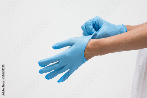 Woman doctor putting blue latex medical gloves on white background.Surgeon wearing gloves before surgery at operating room.Risk and infection control concept.