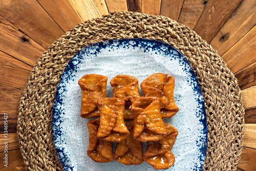  Top view of typical sweets of Spanish gastronomy on rustic wooden table and polka dot plate (Pestiños) photo