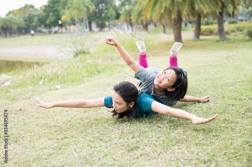 Portrait Asian mother and daughter exercise in the garden.Sporty woman and child playing on the green grass.Outdoor relaxation and happiness family time concept.
