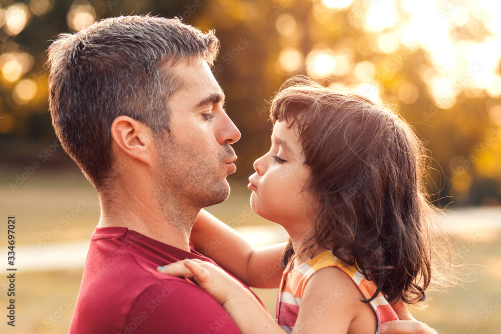 Portrait of father holding daughter in his hands and hugging each other outdoors. Portrait of father holding daughter in his hands and hugging each other outdoors.