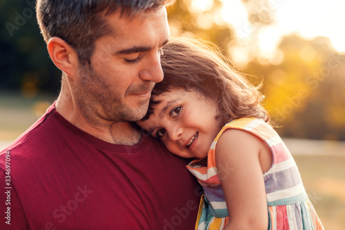 Portrait of father holding daughter in his hands and hugging each other outdoors.