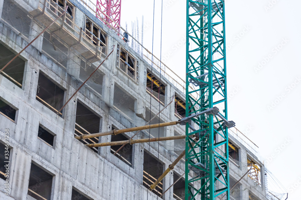 The supports and fastenings supporting the construction crane are installed on the wall of the building and at the windows. The supports and fastenings supporting the construction crane are installed on the wall of the building and at the windows.