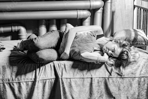 The girl lies on the bed. A young woman suffers from loneliness. Portrait of a depressed woman.