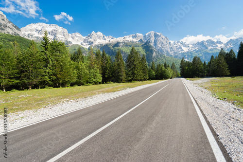 Road in forest to Mountain with snow-capped peaks.