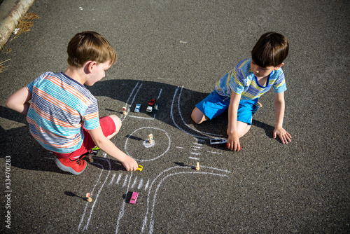 Two brothers sibling kid boy having fun with picture drawing traffic car with chalks. Creative leisure for children outdoors in summer. Difficult traffic rules education friendship concept photo