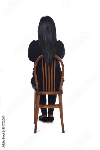 rear view of a woman sitting on chair on white background, arms crossed photo