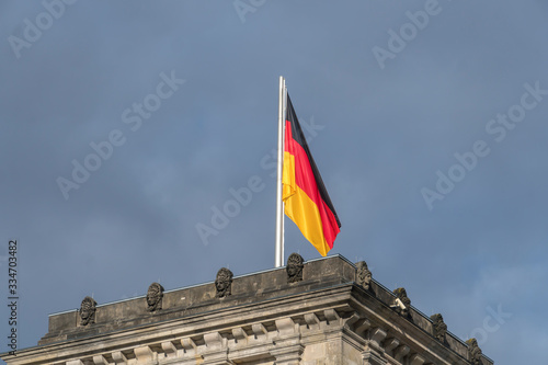 German flag fluttering against cloudy sky on the top of the tower in Berlin Bundestag Reichstag or Bundestag  seat of the German Parliament