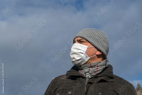 Disease outbreak, coronavirus covid-19 pandemic. Close up portrait from below of a man posing outdoors protecting his face with a mask © cineberg