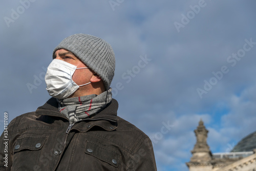 Adult man wearing a medical protective mask on his face posing alone outside the Berlin Reichstag building during the city's lockdown © cineberg