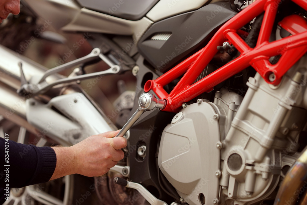 Fototapeta premium Technician hands repairing motobike, doing repair service, maintenance worker repairing vehicle with wrench, service and maintenance motocycle check