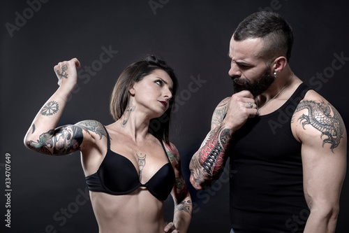 coppia di ragazzi tatuati si guardano con sospetto, isolati su sondo nero