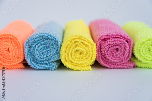 Colorful microfiber cloth, folded in the rollers. The fabrics are laid out in a row. The view from the top. Background texture of the fabric.