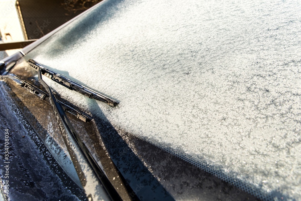 Frozen car windshield covered with ice and snow on a spring day. Frosty morning. Spring frost on the car. Ice scraping. Frozen car windshield covered with ice and snow on a spring day. Frosty morning. Spring frost on the car. Ice scraping.