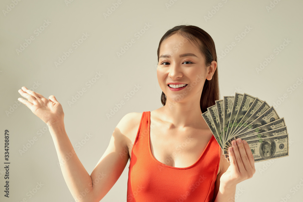 Portrait of an excited beautiful young woman standing isolated over light background, showing money banknotes Portrait of an excited beautiful young woman standing isolated over light background, showing money banknotes