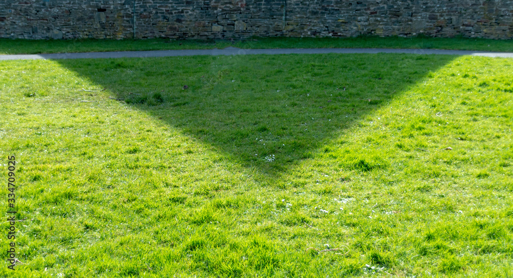 Obraz premium A close up view of the shadow of the church building on the grass in the open park next door to it