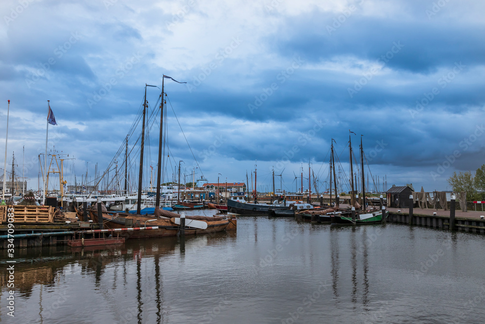 Boat in harbor in Urk city in Holland. Docks where ships are repaired. The background is a blue sky with clouds.