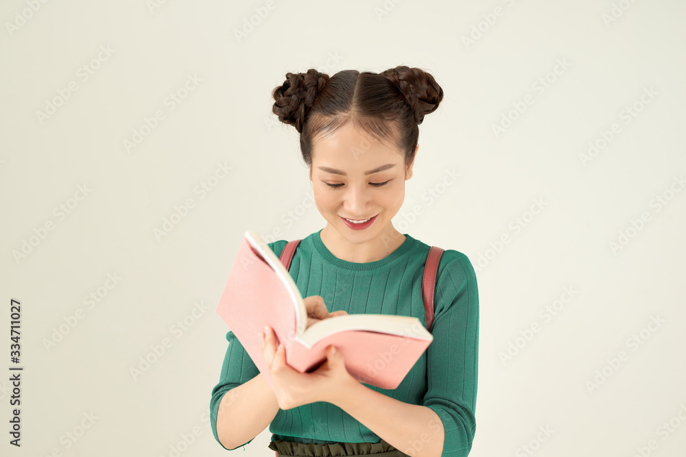 Cute happy student ponder, holding open textbook, isolated on gray background, youth lifestyle, education and back to school concept Cute happy student ponder, holding open textbook, isolated on gray background, youth lifestyle, education and back to school concept