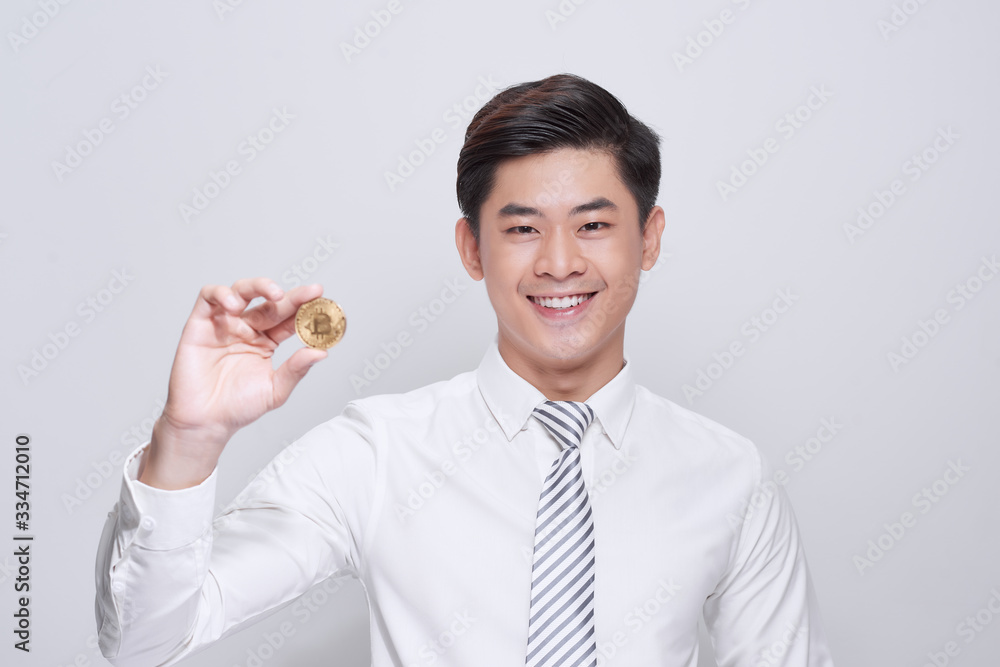 Young handsome businessman holding bitcoin standing over isolated white background Young handsome businessman holding bitcoin standing over isolated white background