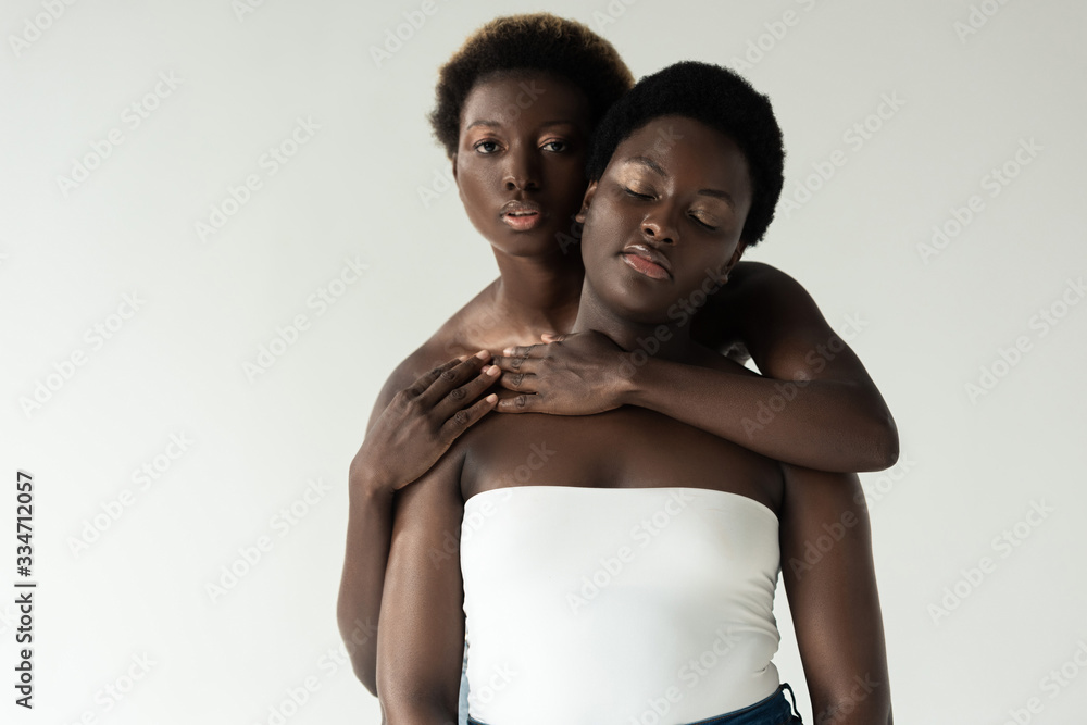 african american women in tops hugging isolated on grey african american women in tops hugging isolated on grey