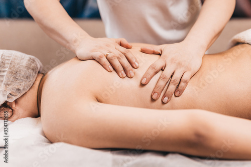 Back massage technique - close-up of a female masseur's hands