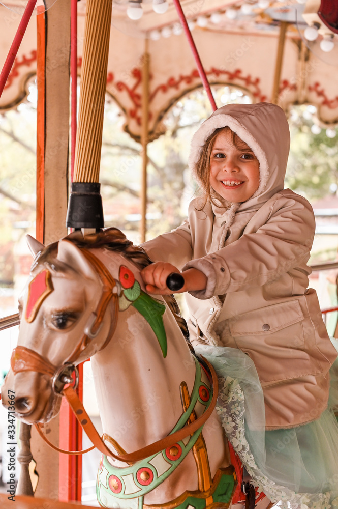 Little girl rides a carousel in an amusement park. Happy child. Little girl rides a carousel in an amusement park. Happy child.